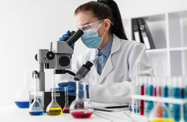 Lab technician analysing a sample under the microscope